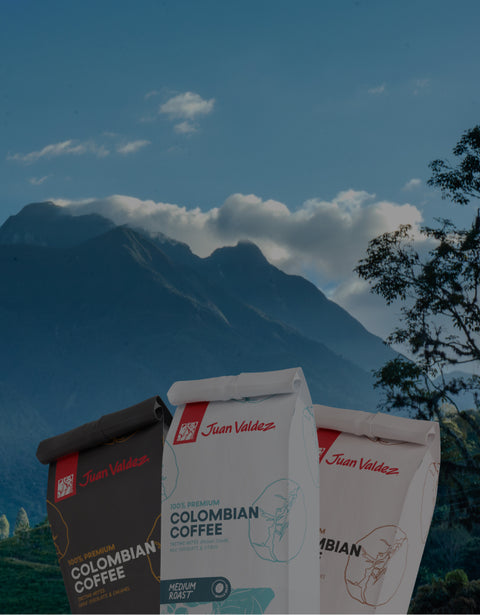 Three coffee bags with 'Juan Valdez' branding against a mountainous landscape.
